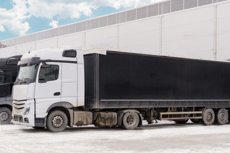 A white truck with a black awning is loading or unloading near a logistics company. Shipping and...