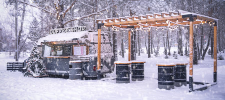 A charming and cozy food truck is beautifully set in a serene winter landscape, surrounded by...