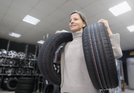 Woman carries tires at tire store in preparation for tire change season and makes a purchase for her...