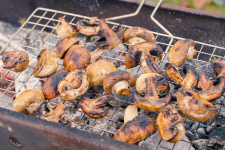 grill grate with fried mushrooms and champignons in close-up. The mushrooms are evenly browned, showcasing their juicy texture.の写真素材