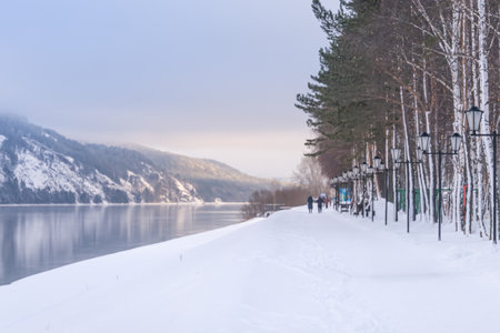 Divnogorsk city embankment in winter. A path along the river and winter mountains in the suburbs of Krasnoyarsk, a cozy riverbank in Russia. Experience the beauty of a Winter Wonderland with a serene snowy riverbank walk in natureの写真素材
