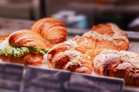 Fresh golden croissants made of puff pastry with almond flakes and powdered sugar in close-up on a...