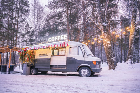 A cozy coffee shop in a winter park on Christmas Eve. A food truck in the woods in winter. High quality photoの写真素材