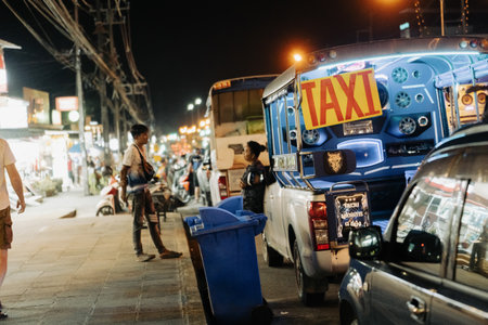 Khao Lak, Thailand, 24 11 2025: Kaolak Night Street - tuk tuk taxi drivers are chatting near their Songteo pickups, waiting for tourist customers on a busy night street. High quality photoのeditorial素材