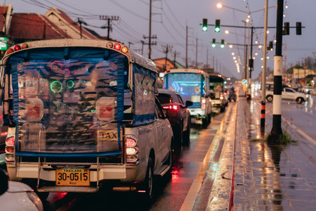 Khao Lak, Thailand, 24 11 2025: Vehicles line the road in Thailand as rain falls on the street. Taxis with bright lights wait for the green signal while people go about their evening routines. Highのeditorial素材