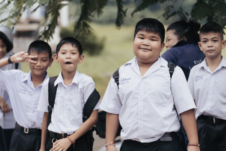 Khao Lak, Thailand, 24 11 2025: Thai school boys in school uniforms wait to be taken home after school. They are happy and contented since their studies are over. High quality photoのeditorial素材