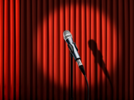 Microphone under spotlight over red curtainsの写真素材