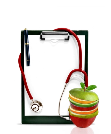 Healthy concept with stethoscope and slice of fruits in front of a clip boardの写真素材