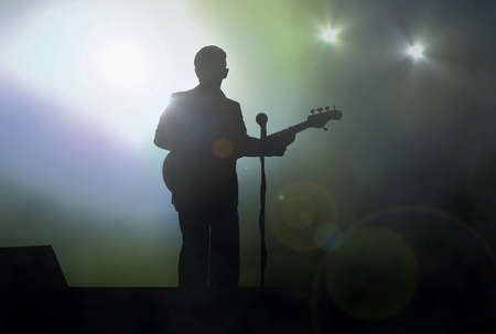 Guitarist on stage performing live under spotlightの写真素材