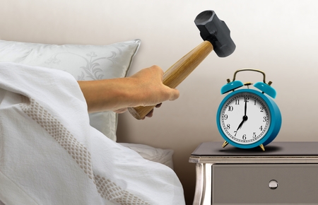 Man smashing alarm clock with sledge hammerの写真素材