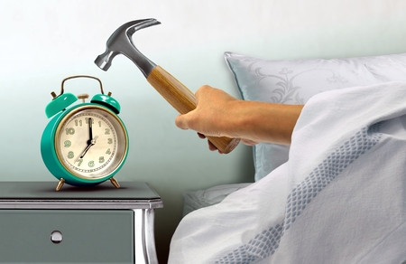 Hand hitting alarm clock with hammerの写真素材