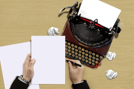 Vintage typewriter with author hand checking a paper sheetsの写真素材
