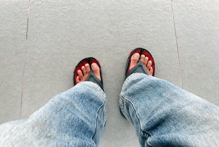 Man feet top view wearing jeans and sandals