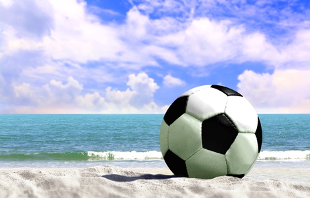Soccer ball at the beach with cloudy blue skyの写真素材