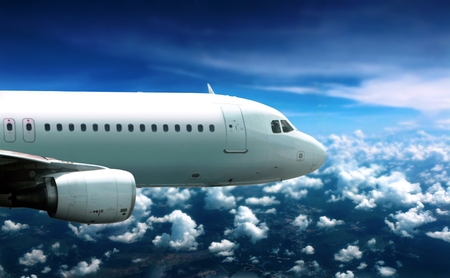 Airplane flying in cloudy sky belowの写真素材