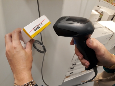 hand holding scanner and scans product barcode with laserの写真素材