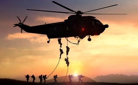 Military commando helicopter drops in silhouette during sunsetの写真素材