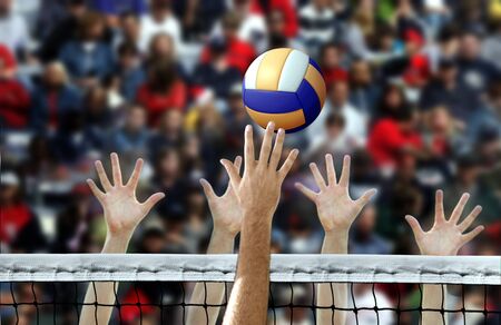Volleyball spike with hands blocking over the netの写真素材