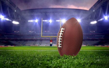 American football ball in stadium at night under spotlightsの写真素材