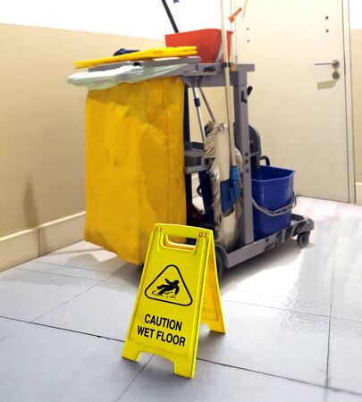 wet floor signage with cleaning tools in backgroundの写真素材