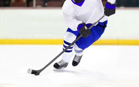 Ice hockey player dribbling puck on rinkの写真素材