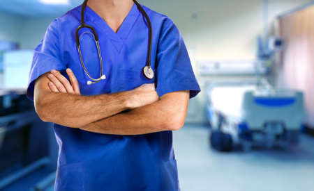 Doctor in medical scrubs standing with arms crossed in the hospital emergency roomの写真素材