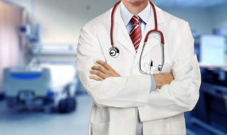Doctor in medical coat standing with arms crossed in the hospital wardの写真素材