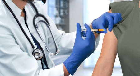 Doctor injecting patient's arm in the hospital clinic using syringeの写真素材