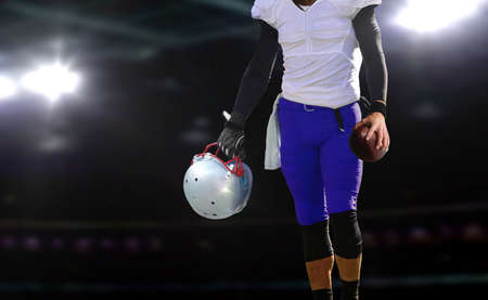 football player holding ball and helmetの写真素材
