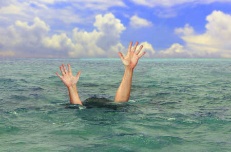 drowning man hands stretched out to the surface for help at seaの写真素材