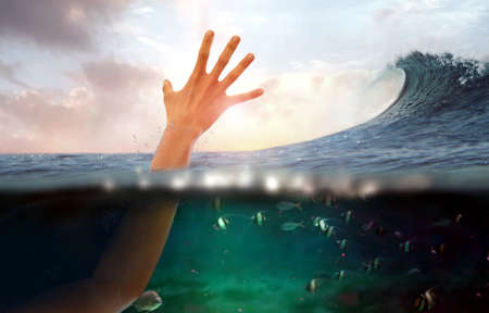 Hand of person drowning in water at seaの写真素材