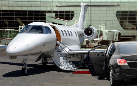 Private jet waiting for passenger with black limo in airportの写真素材