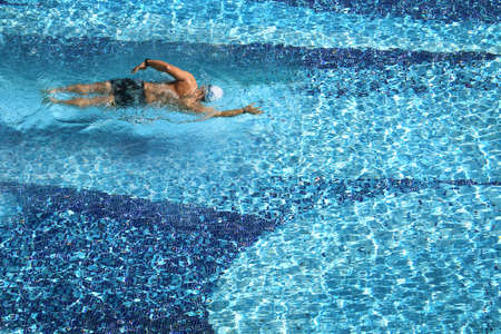 Aerial view of a man swimming  in a pool on hot sunny day.の写真素材