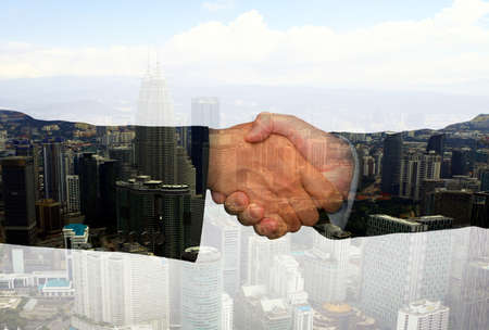 Business hand shake concept with abstract office buildings in backgroundの写真素材
