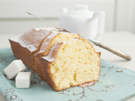 Homemade powedered cake on cyan napkin with floweres and white background. Selective focus.の写真素材