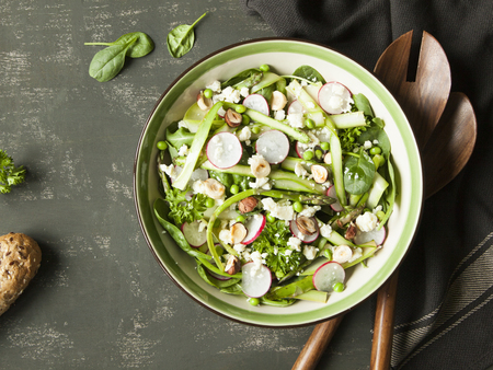 Spring vegetable salad with asparagus, zucchini, radish, spinach and goat cheese on dark background.の写真素材
