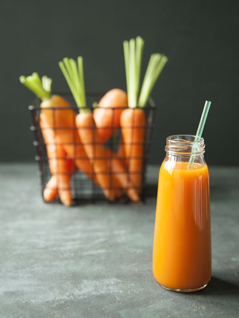 A bottle of fresh carrot juice with fresh carrots on dark background.の写真素材