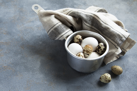 Metallic sauce pan with raw hen and quail eggs on dark shabby background.の写真素材
