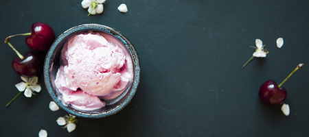 Cherry ice cream scoop in bowl, fresh cherry berries and flowers on dark green background with copy space. の写真素材