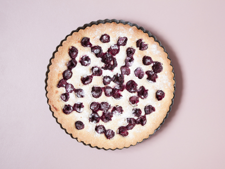 Whole homemade cherry cake on pastel pink background. Minimal. Flat lay.の写真素材