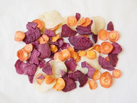 Dried vegetable (carrot, potato, beetroot) chips on paper. Flat lay. Minimal.の写真素材
