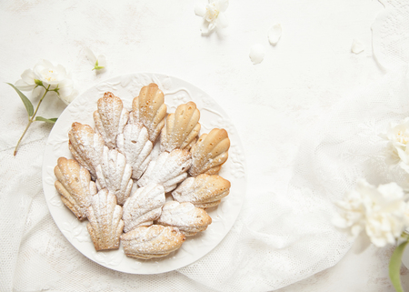 Homemade French cookies (cakes) Madeleine with jasmine tea on white background with fresh syringa floweres. Selective focus.の写真素材