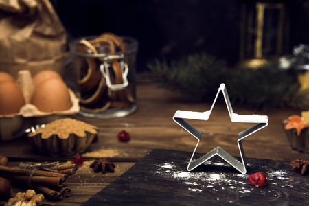Winter (Christmas) baking ingredients on dark rustic background. Flour, eggs, dried fruit, nuts, spices.の写真素材