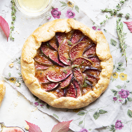 Crostata (pie) with cheese, figs, honey and thyme on grey background. Flat lay. Seasonal autumn dessert.の写真素材