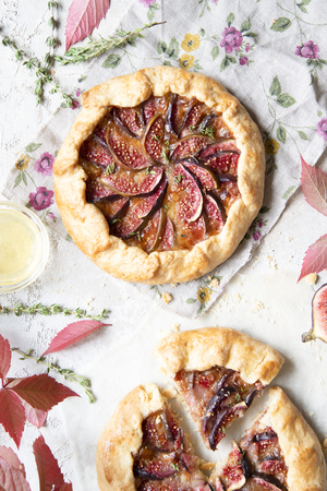 Crostata (pie) with cheese, figs, honey and thyme on grey background. Flat lay. Seasonal autumn dessert. Copy space.の写真素材