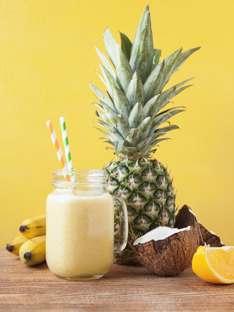 Fresh exotic smoothie with fruits and coconut milk on yellow background.の写真素材