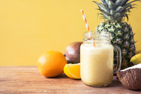 Fresh exotic smoothie with fruits and coconut milk on yellow background. Copy space.の写真素材