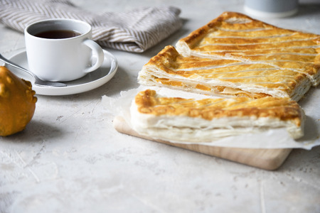 Puff pastry pie with pumpkin, onion and cheese on grey background. Minimal. Selective focus. Copy space.の写真素材