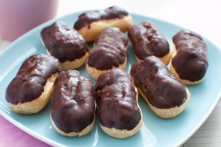 Plate with eclairs with chocolate coating and custard