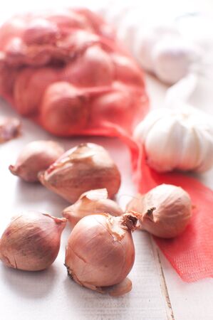 Garlic bulbs and shallot onion with mesh bagの写真素材